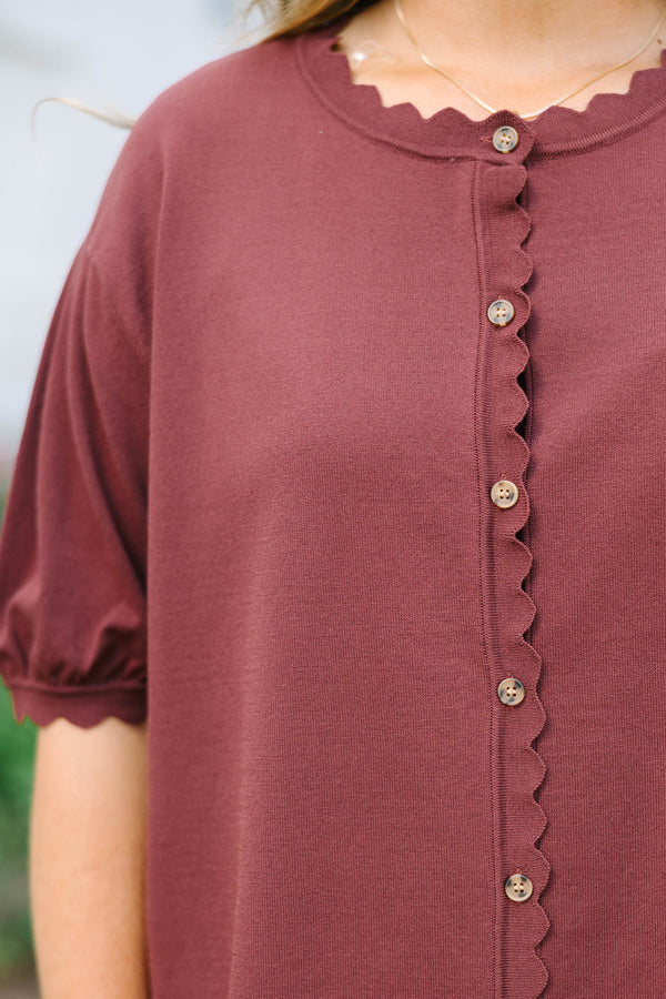 Plus size woman in a brown short sleeve cardigan with scalloped edges and a button-down front.