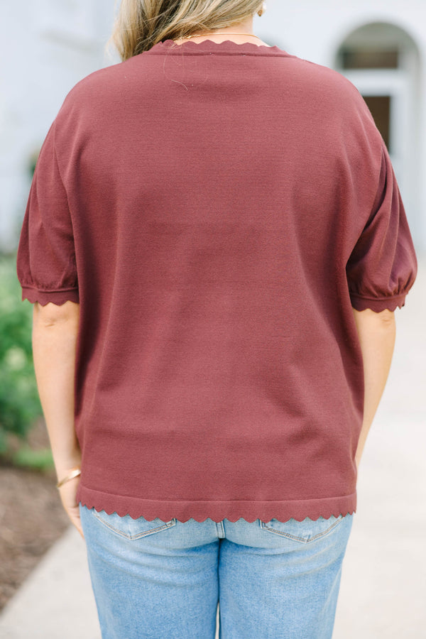 Plus size woman in a brown short sleeve cardigan with scalloped edges and a button-down front.