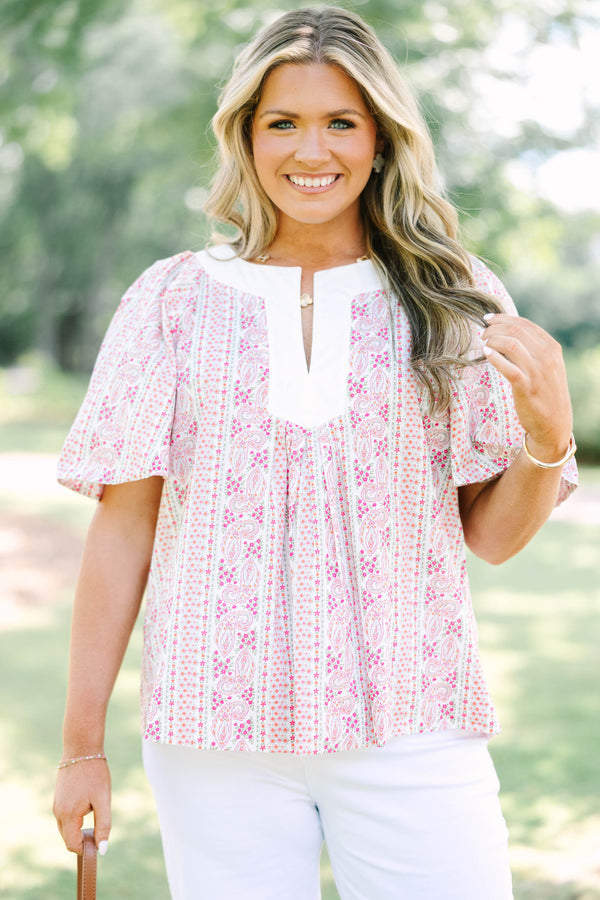 Plus Size pink paisley top with a white V-neckline, short flutter sleeves, and white pants.
