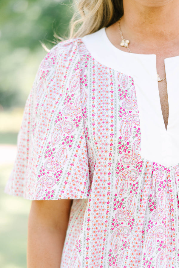 Plus Size pink paisley top with a white V-neckline, short flutter sleeves, and white pants.