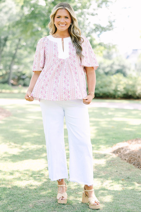 Plus Size pink paisley top with a white V-neckline, short flutter sleeves, and white pants.