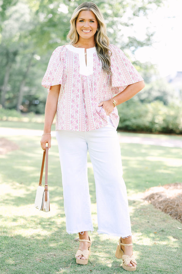 Plus Size pink paisley top with a white V-neckline, short flutter sleeves, and white pants.