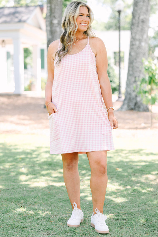 Plus size pink gingham athleisure dress with front pockets and a flowy, comfortable fit.