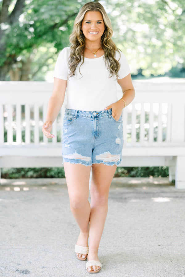 Plus Size medium wash denim shorts with heavy distressing and frayed hems.