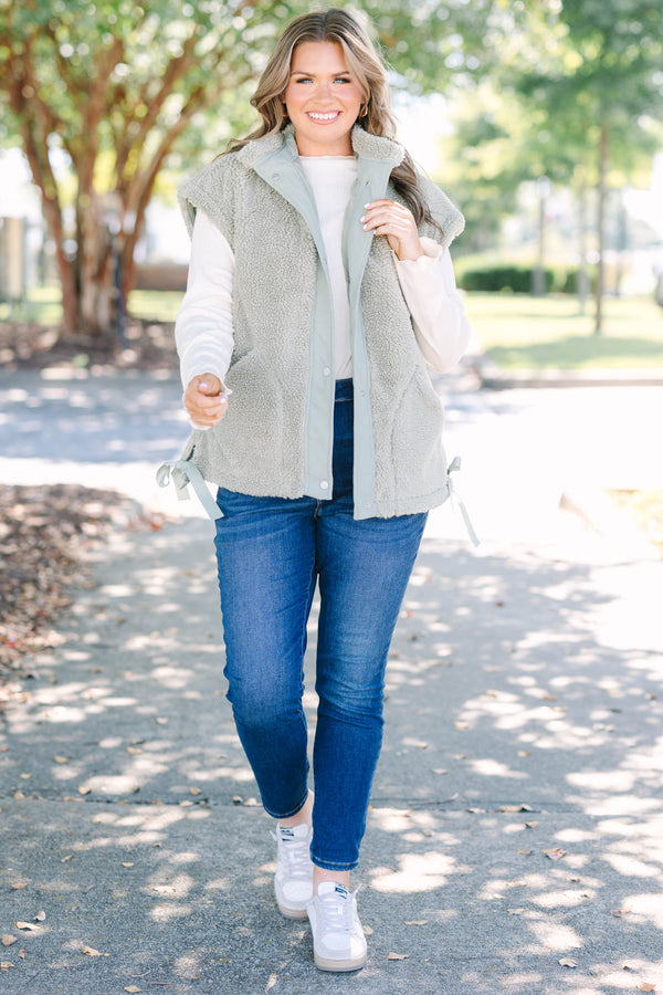 Plus size olive green sherpa vest with a zip-up front, snap buttons, and cozy textured fabric.