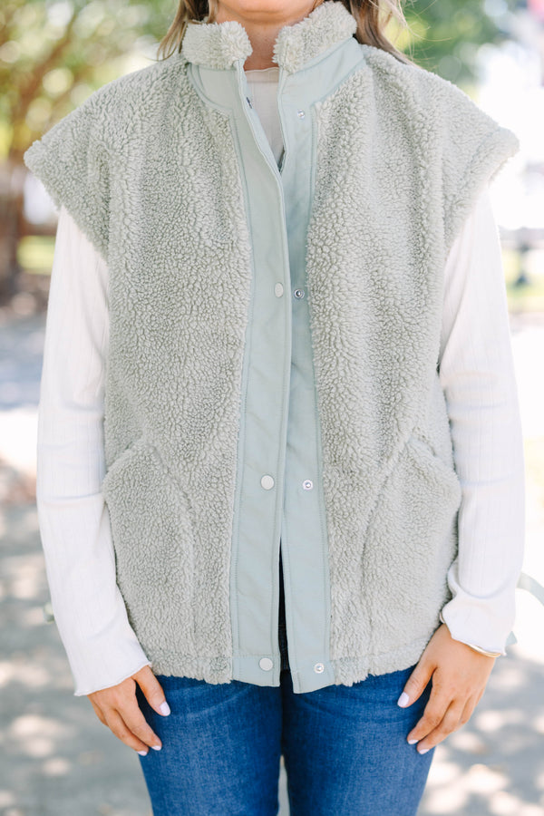 Plus size olive green sherpa vest with a zip-up front, snap buttons, and cozy textured fabric.