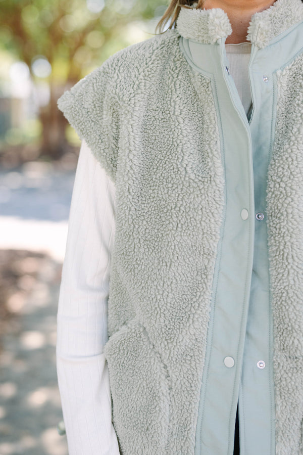 Plus size olive green sherpa vest with a zip-up front, snap buttons, and cozy textured fabric.