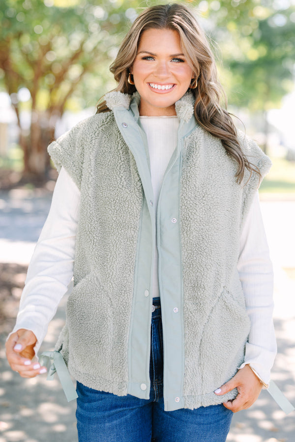 Plus size olive green sherpa vest with a zip-up front, snap buttons, and cozy textured fabric.