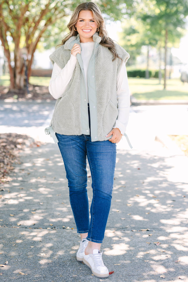 Plus size olive green sherpa vest with a zip-up front, snap buttons, and cozy textured fabric.