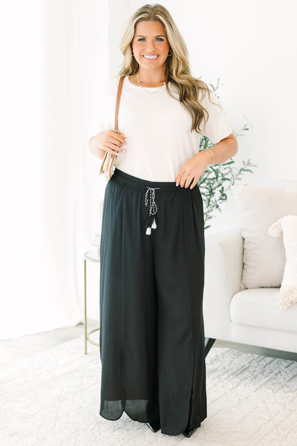 Plus size black wide-leg pants with a flowy fit, smocked drawstring waist, and tassel details.