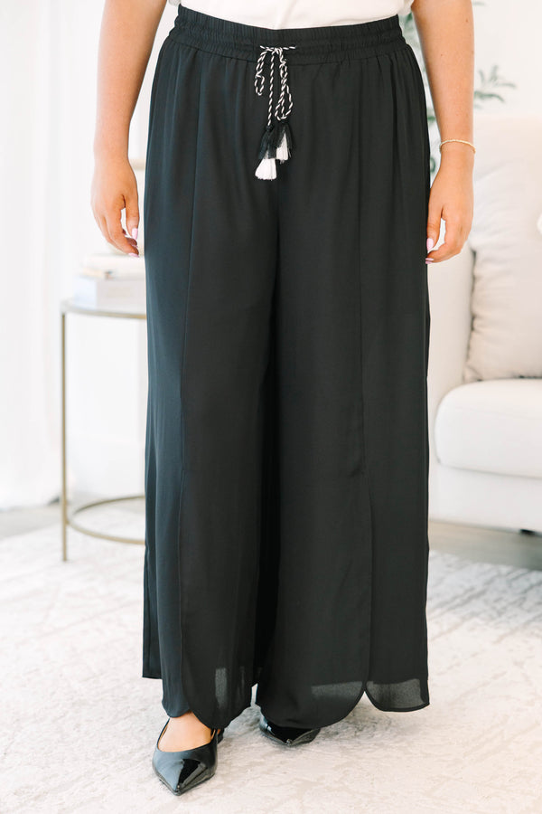 Plus size black wide-leg pants with a flowy fit, smocked drawstring waist, and tassel details.