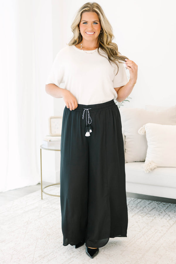 Plus size black wide-leg pants with a flowy fit, smocked drawstring waist, and tassel details.