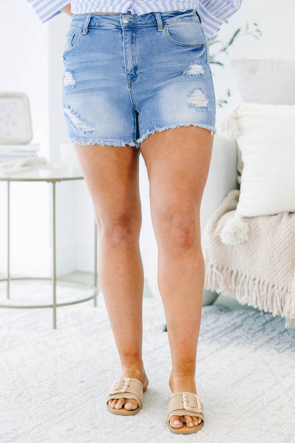 Plus size light wash denim shorts with distressing, frayed hem, and a comfortable stretchy fit.