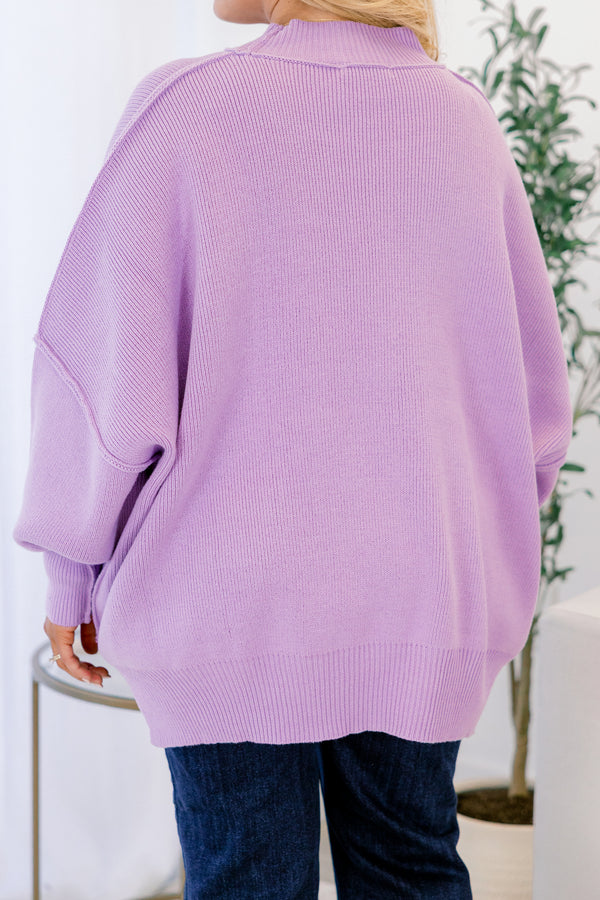 Person wearing a light purple sweater in an indoor setting