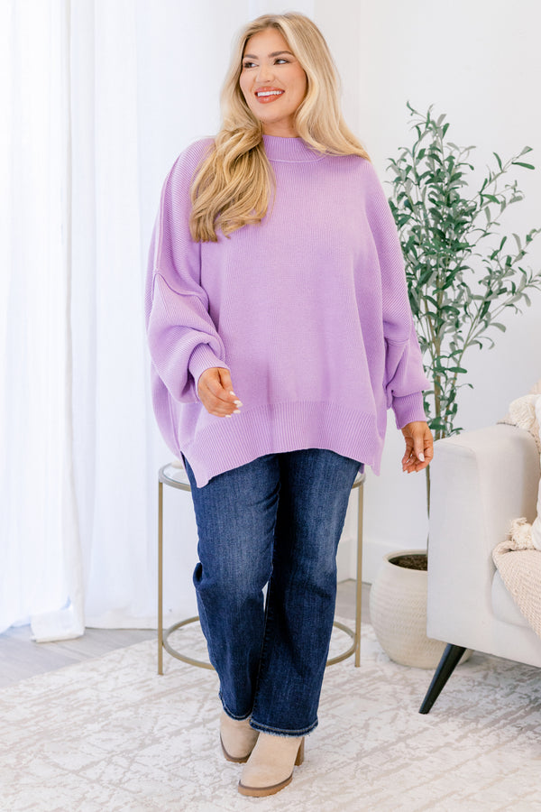Woman wearing a purple sweater and blue jeans in a home setting