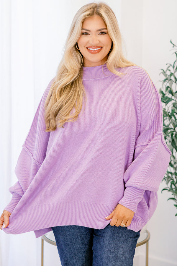 Woman wearing a purple sweater in a bright room with a plant in the background