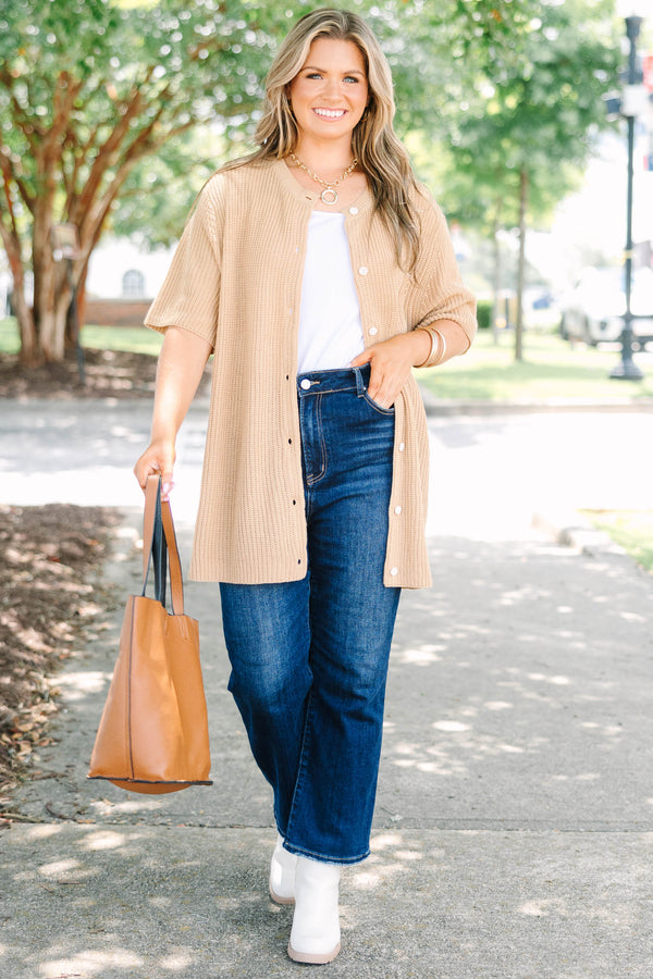 Plus size woman in a tan, short-sleeve knit cardigan with a flowy fit and button-down front.