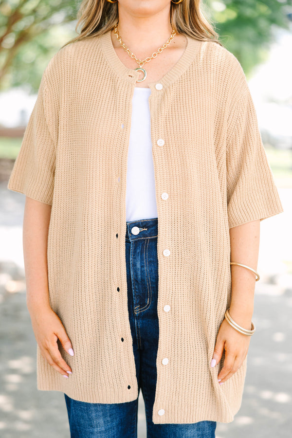 Plus size woman in a tan, short-sleeve knit cardigan with a flowy fit and button-down front.
