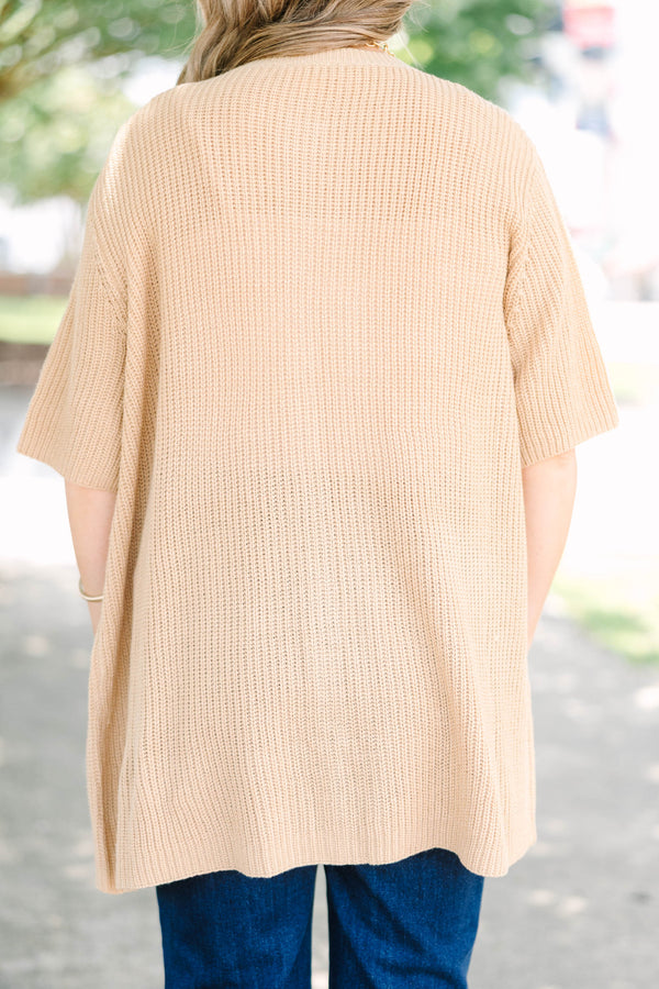 Plus size woman in a tan, short-sleeve knit cardigan with a flowy fit and button-down front.