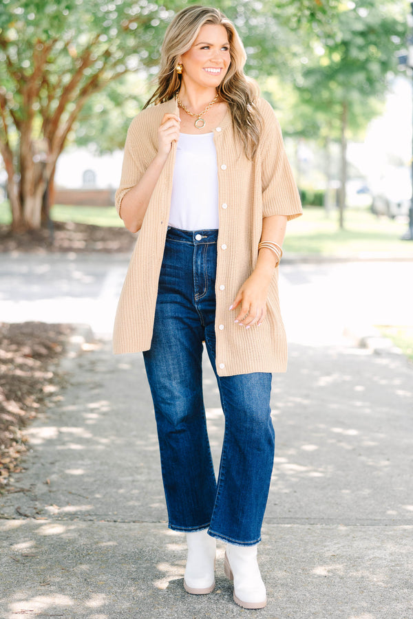 Plus size woman in a tan, short-sleeve knit cardigan with a flowy fit and button-down front.