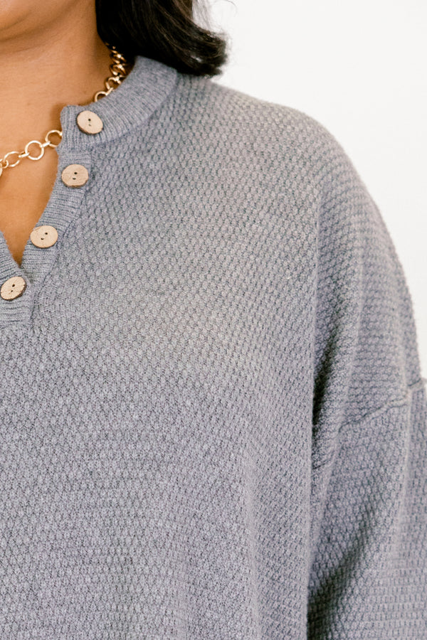 Close-up of a textured blue sweater with button details on a plain background