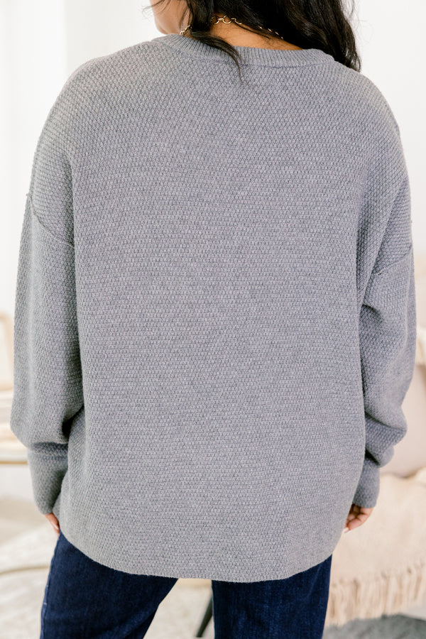 Person wearing a gray textured sweater with a blurred background