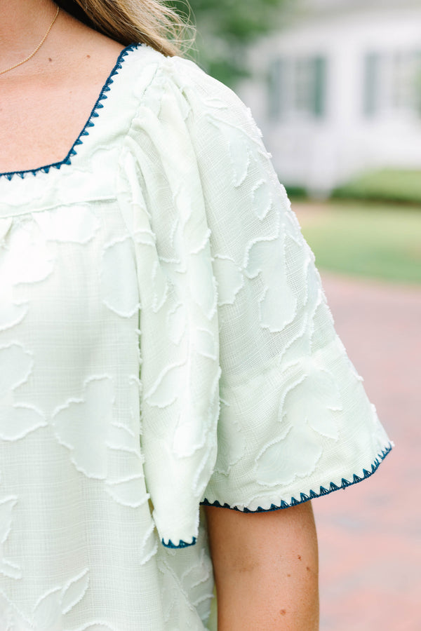 Plus Size light green floral textured top with navy scalloped trim and short flutter sleeves.