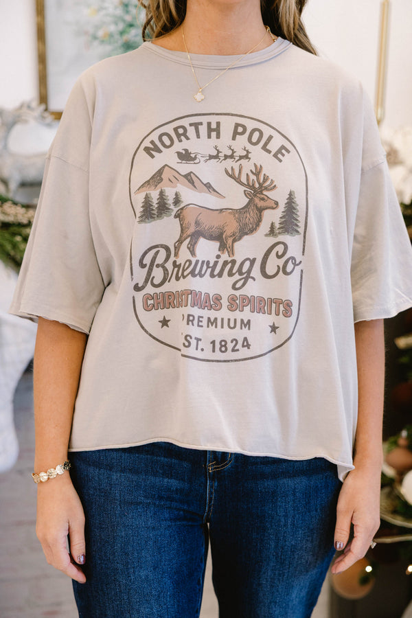 Chic Soul plus size clothing, stone tan short sleeve slightly cropped vintage wash tee with “North Pole Brewing Co. Christmas Spirits Premium Ext. 1824” text on the front with a reindeer mountains and tree