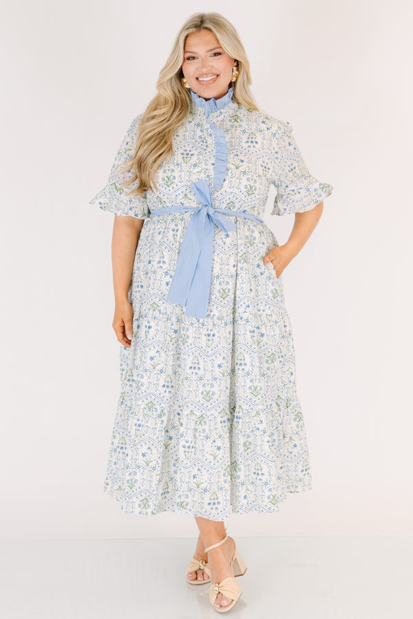 Chic Soul plus size clothing, blue maxi dress with shorts sleeves that flare out a blue multi floral pattern and a blue belt that ties into a bow that goes around the waist as blue ruffling details going along the neckline 
