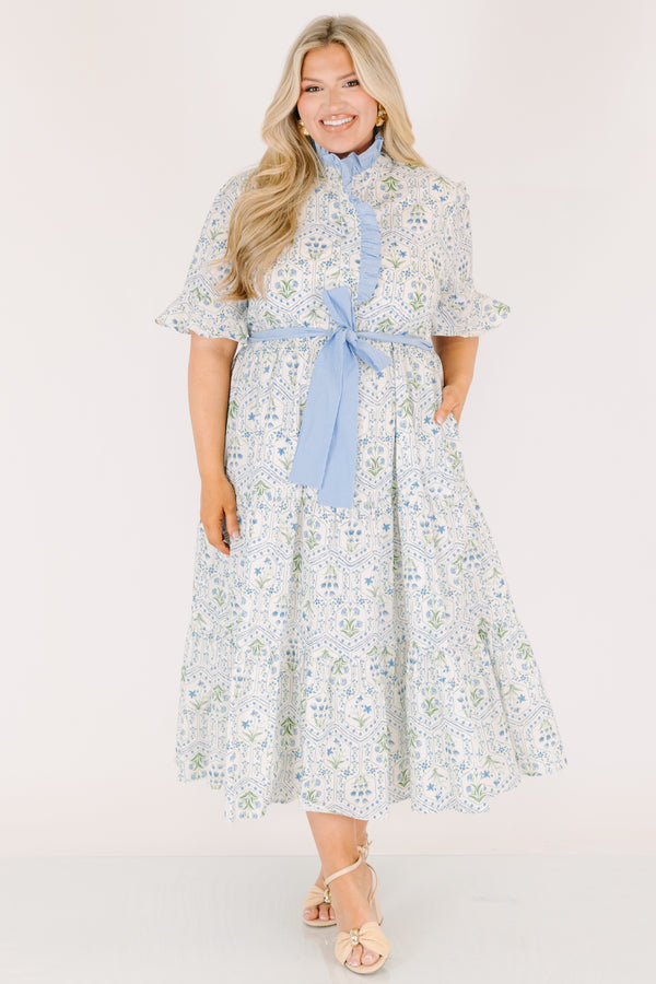 Chic Soul plus size clothing, blue maxi dress with shorts sleeves that flare out a blue multi floral pattern and a blue belt that ties into a bow that goes around the waist as blue ruffling details going along the neckline 