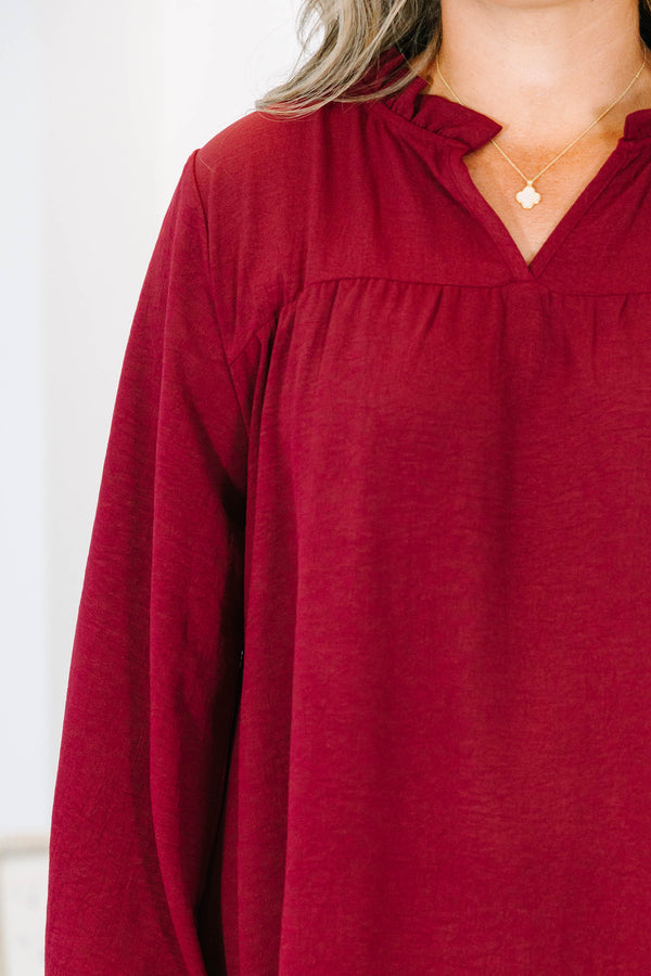 Plus size burgundy flowy long sleeve top with a ruffled V-neckline and relaxed fit.