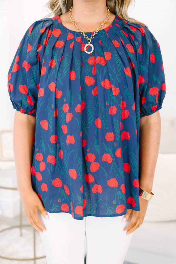 Plus size navy top with red poppy print, flowy fit, and puff sleeves.