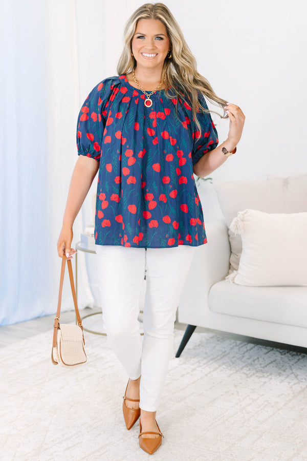 Plus size navy top with red poppy print, flowy fit, and puff sleeves.