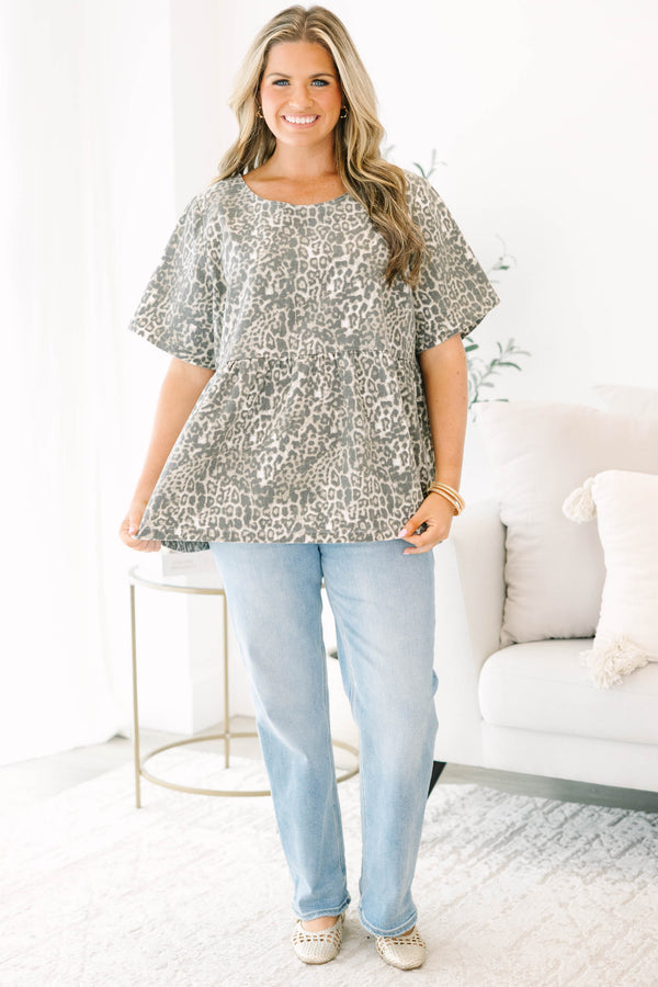 Plus size woman in a light leopard print peplum top with a flowy fit and short sleeves.