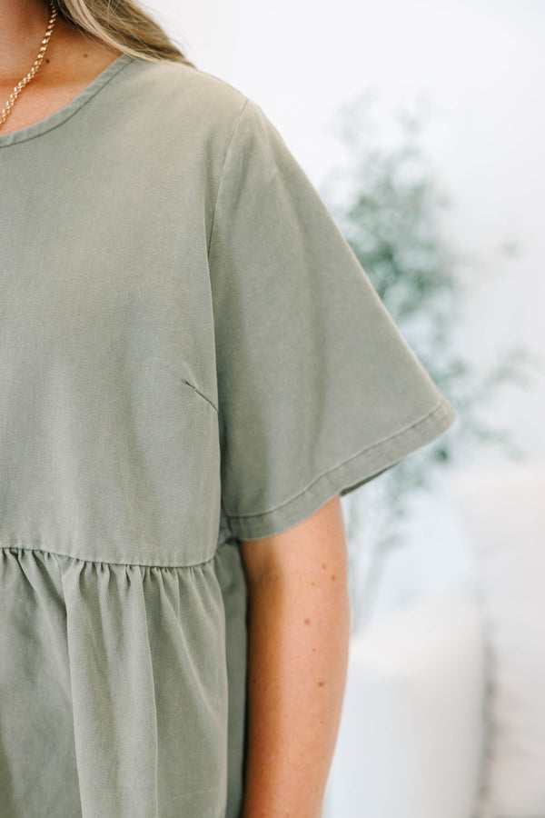 Plus Size olive green short sleeve babydoll top with a round neckline and ruffled waist seam.