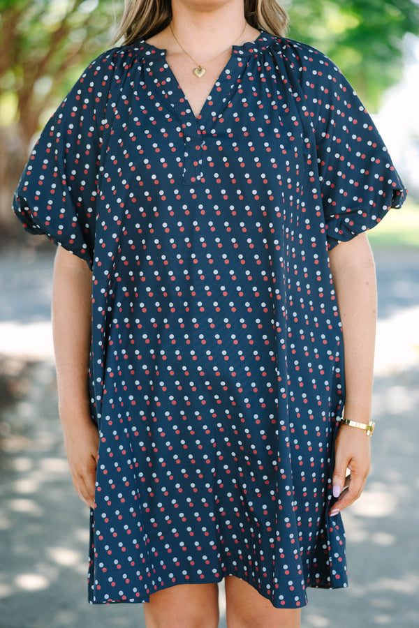 Plus size navy shift dress with red and white polka dots, featuring a flowy fit and V-neckline.