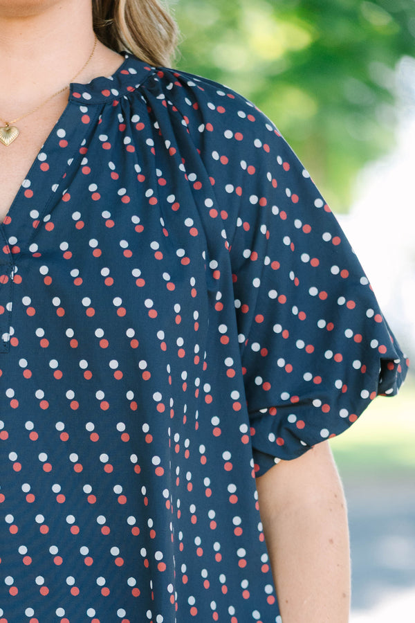 Plus size navy shift dress with red and white polka dots, featuring a flowy fit and V-neckline.