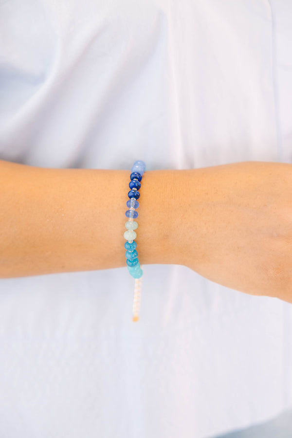 Blue, teal, and white beads on a gold chain and clasp bracelet 