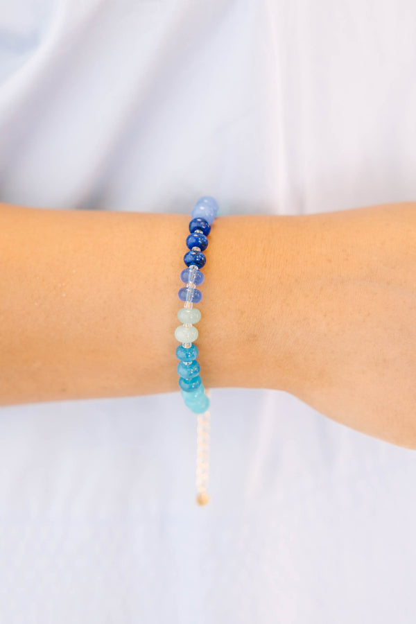 Blue, teal, and white beads on a gold chain and clasp bracelet 
