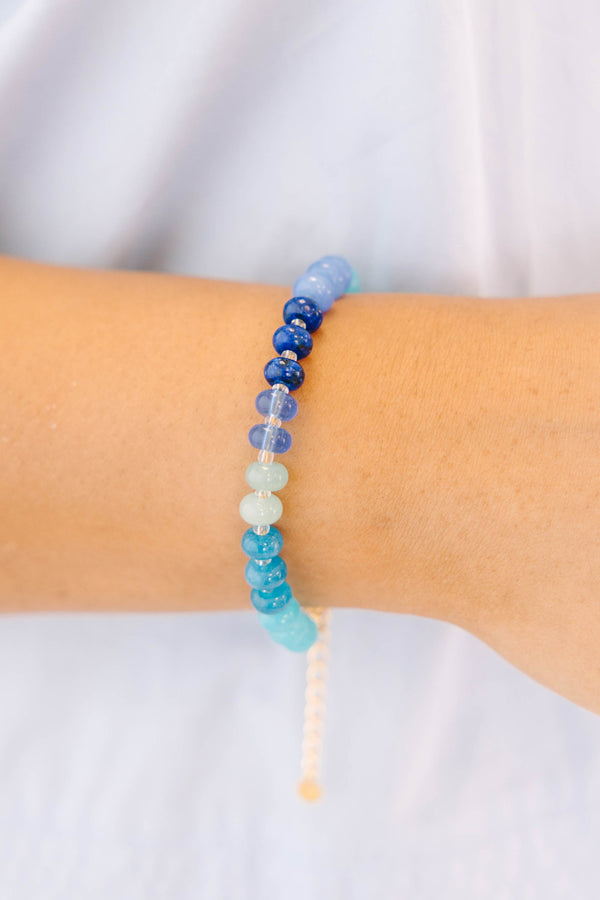 Blue, teal, and white beads on a gold chain and clasp bracelet 