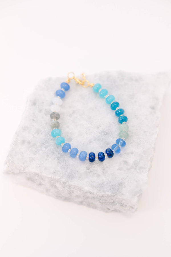 Blue, teal, and white beads on a gold chain and clasp bracelet 