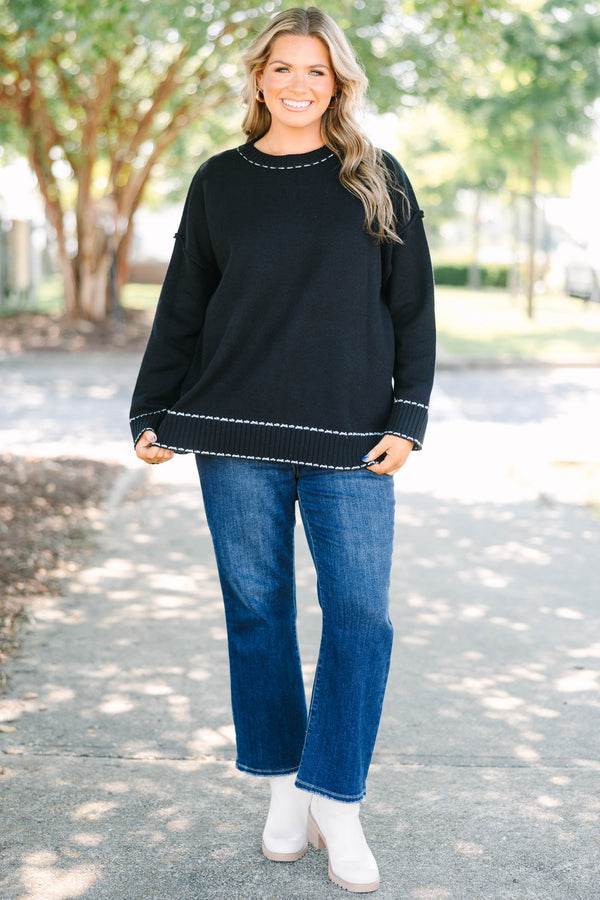 Plus size black knit sweater with white contrast stitching on the neckline, cuffs, and hem.