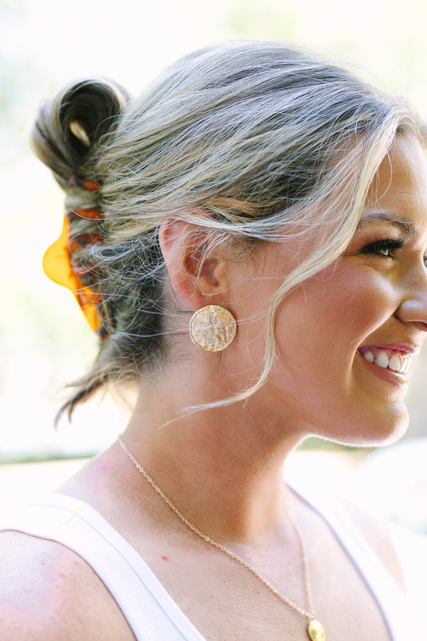 Textured gold round stud earrings with a hammered metallic finish.
