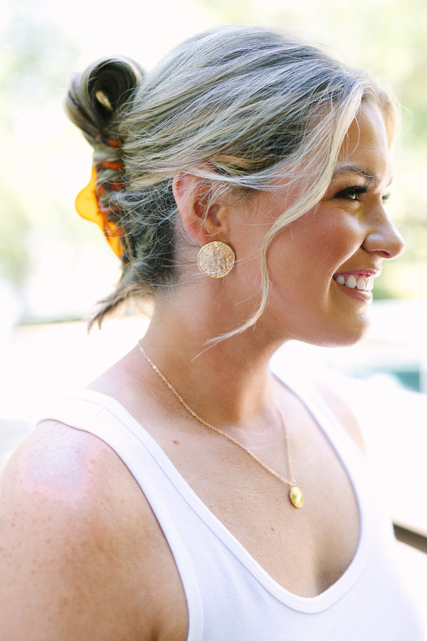 Textured gold round stud earrings with a hammered metallic finish.
