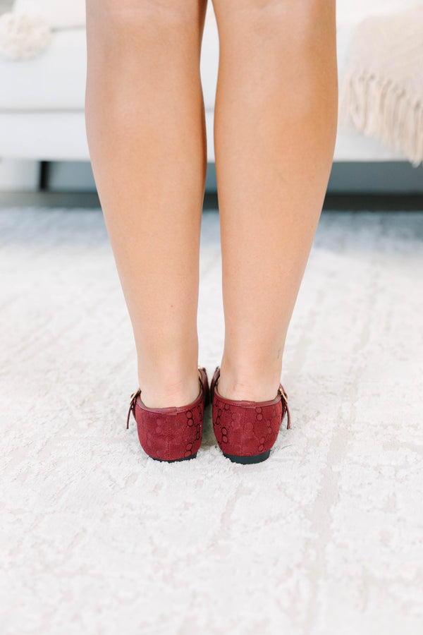 Wine-colored flats with a monogram pattern and gold buckle detail.