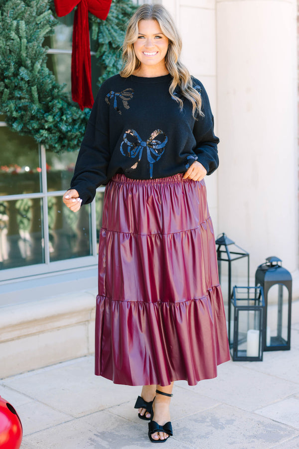 Plus Size black crewneck sweater with sequined bow patterns paired with a burgundy faux leather skirt.