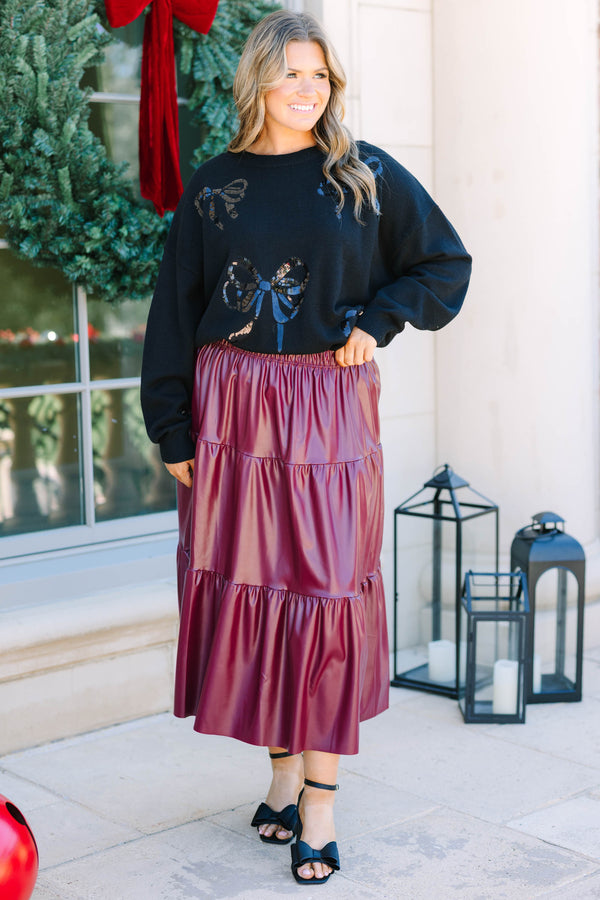 Plus Size black crewneck sweater with sequined bow patterns paired with a burgundy faux leather skirt.