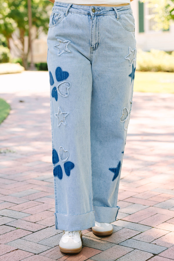 Plus Size light wash wide leg jeans with dark blue star and heart patches and frayed star cutouts.