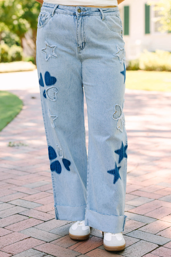 Plus Size light wash wide leg jeans with dark blue star and heart patches and frayed star cutouts.