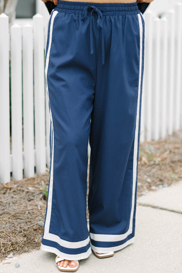 Chic Soul plus size clothing, navy blue long flowy pants with elastic waistband and drawstrings with vertical white lines down the outer sides of the pants that lead into horizontal white lines bordering the bottom of the pants